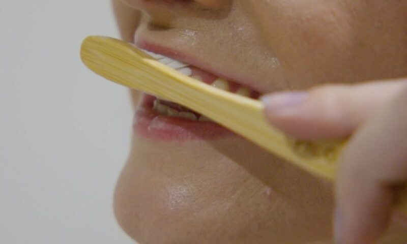 devojka pere zube sa četkicom od bambusa