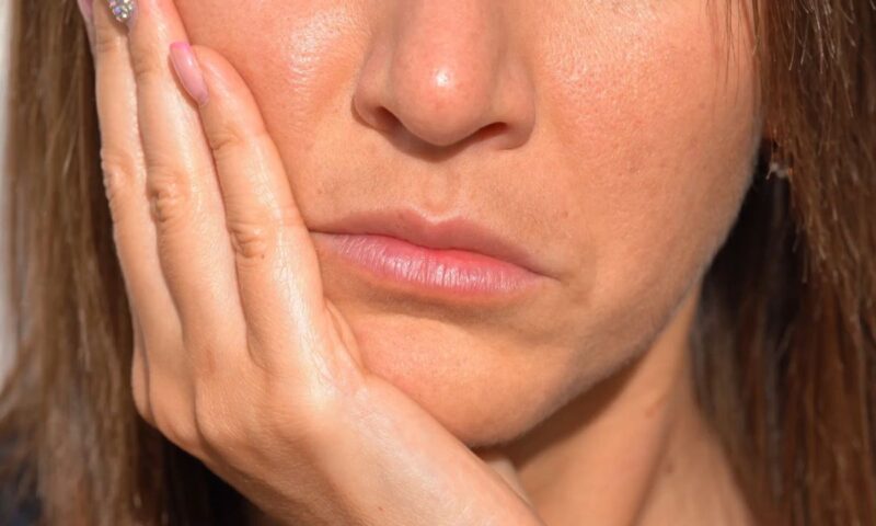 ženska osoba se drži za vilicu nakon vađenja umnjaka